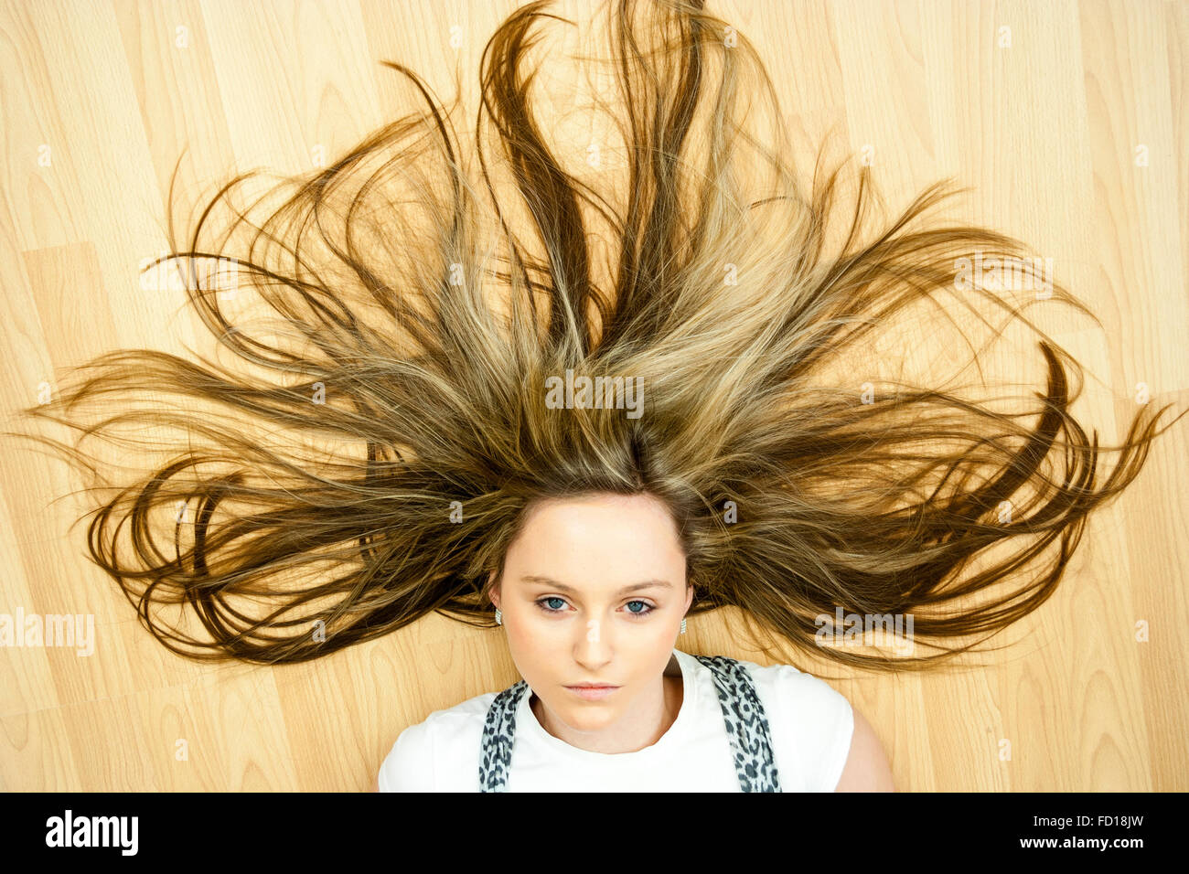 Tête et épaules, blond teenage Blue Eyed Girl laying on floor à directement à l'afficheur. Sèche pulvérisée plus sauvagement le grain du bois-de-chaussée. Banque D'Images