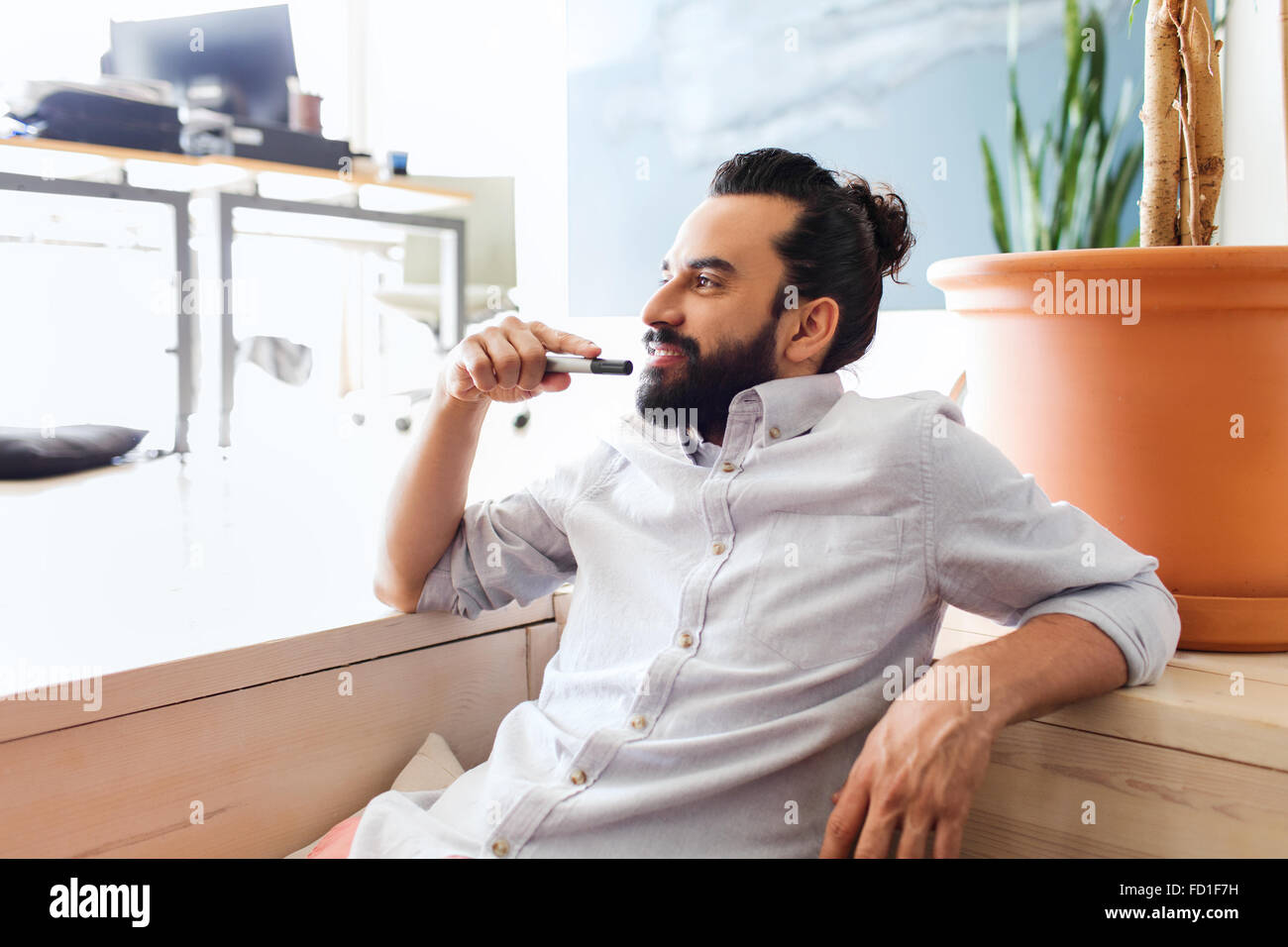 Smiling man avec barbe et cheveux bun at office Banque D'Images