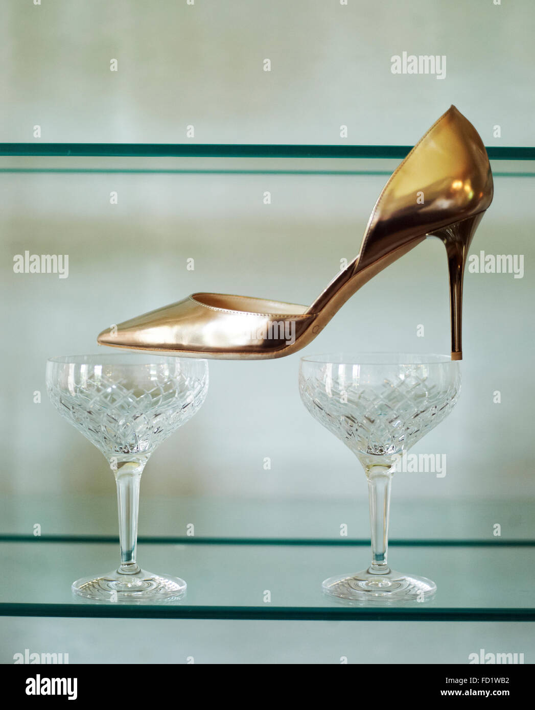 Une chaussure haut talon doré placé sur deux verres à vin Photo Stock -  Alamy