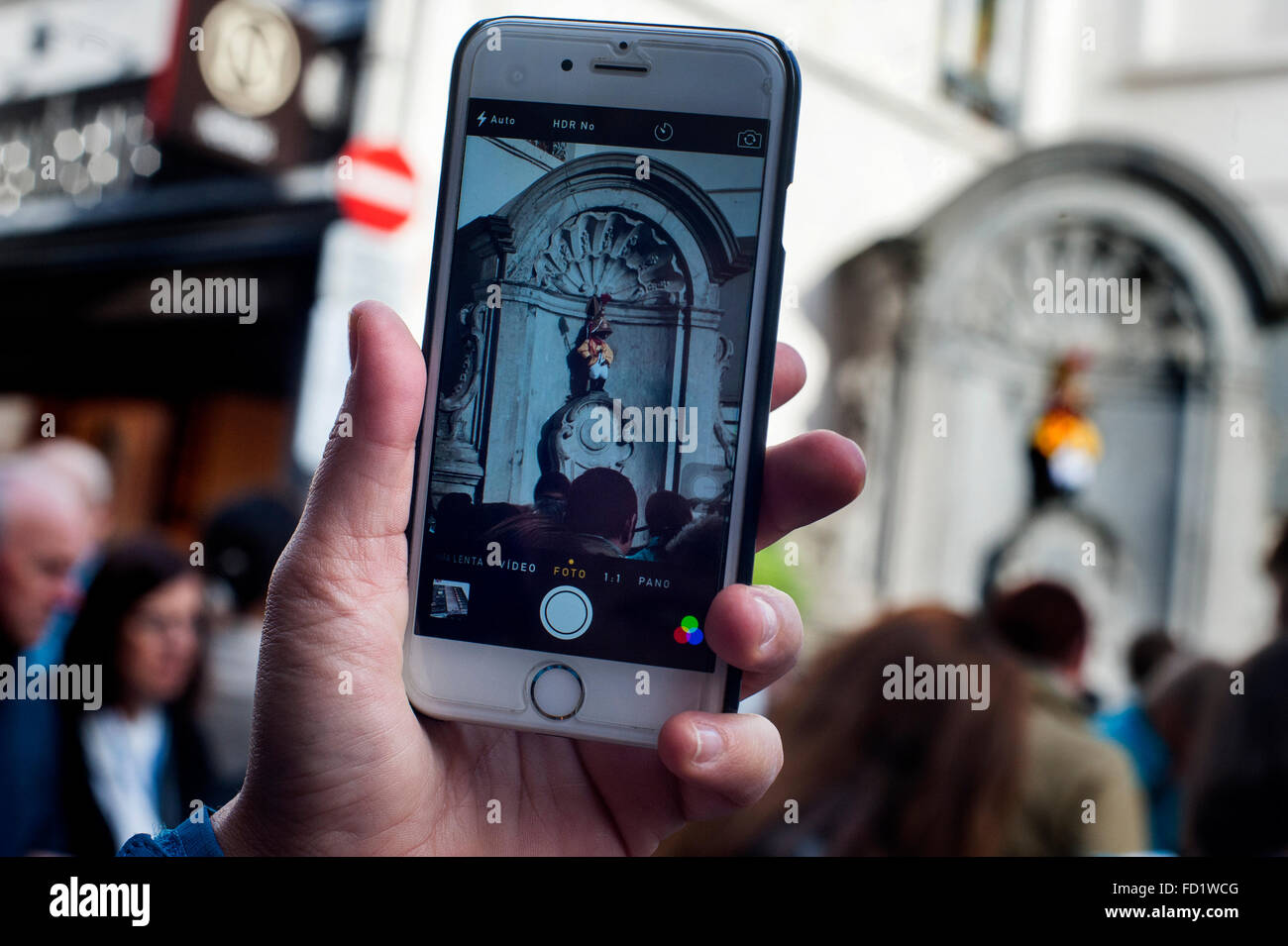 Un touriste prend une photo avec son smartphone à Manneken Pis, l'un des monuments qui malgré sa taille (petite) et la tradition o Banque D'Images