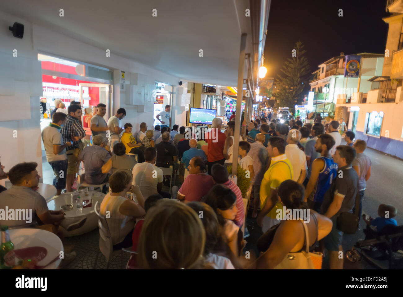Les spectateurs sur la terrasse d'un bar et de regarder l'émission de télévision de la rue d'une partie de soccer en été dans le sud de l'Italie Banque D'Images