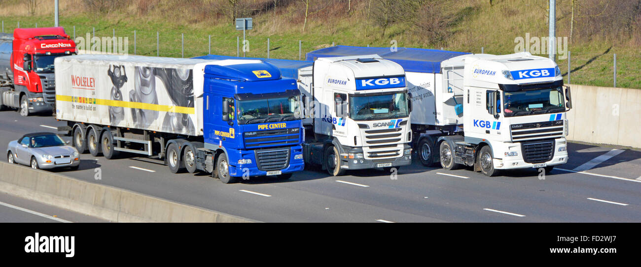 Camions et une voiture de dépassements sur quatre voies de l'autoroute M25 (car obscured plaque) Banque D'Images