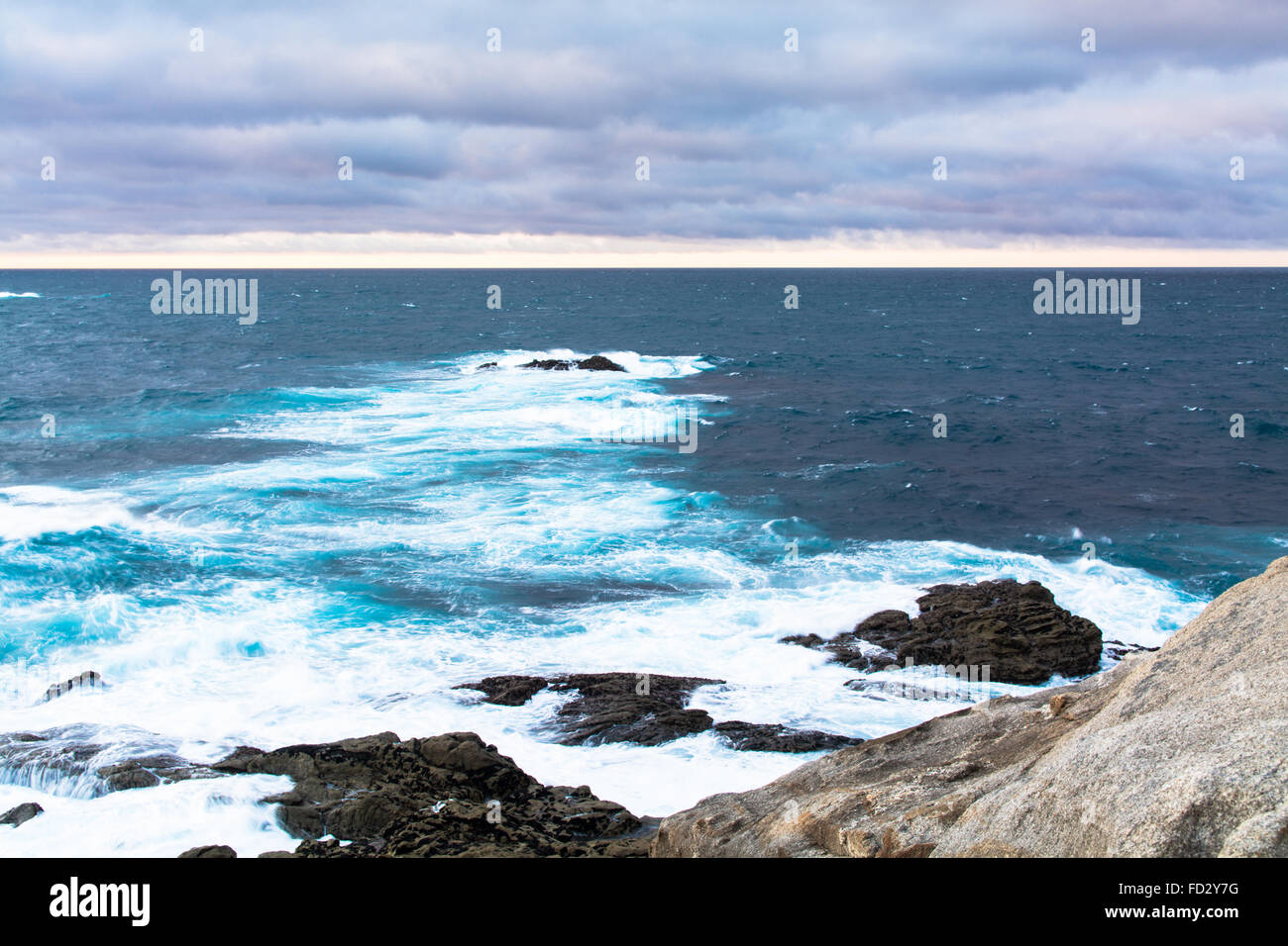 Avis de côte rocheuse avec mousse vagues contre Horizon nuageux Banque D'Images