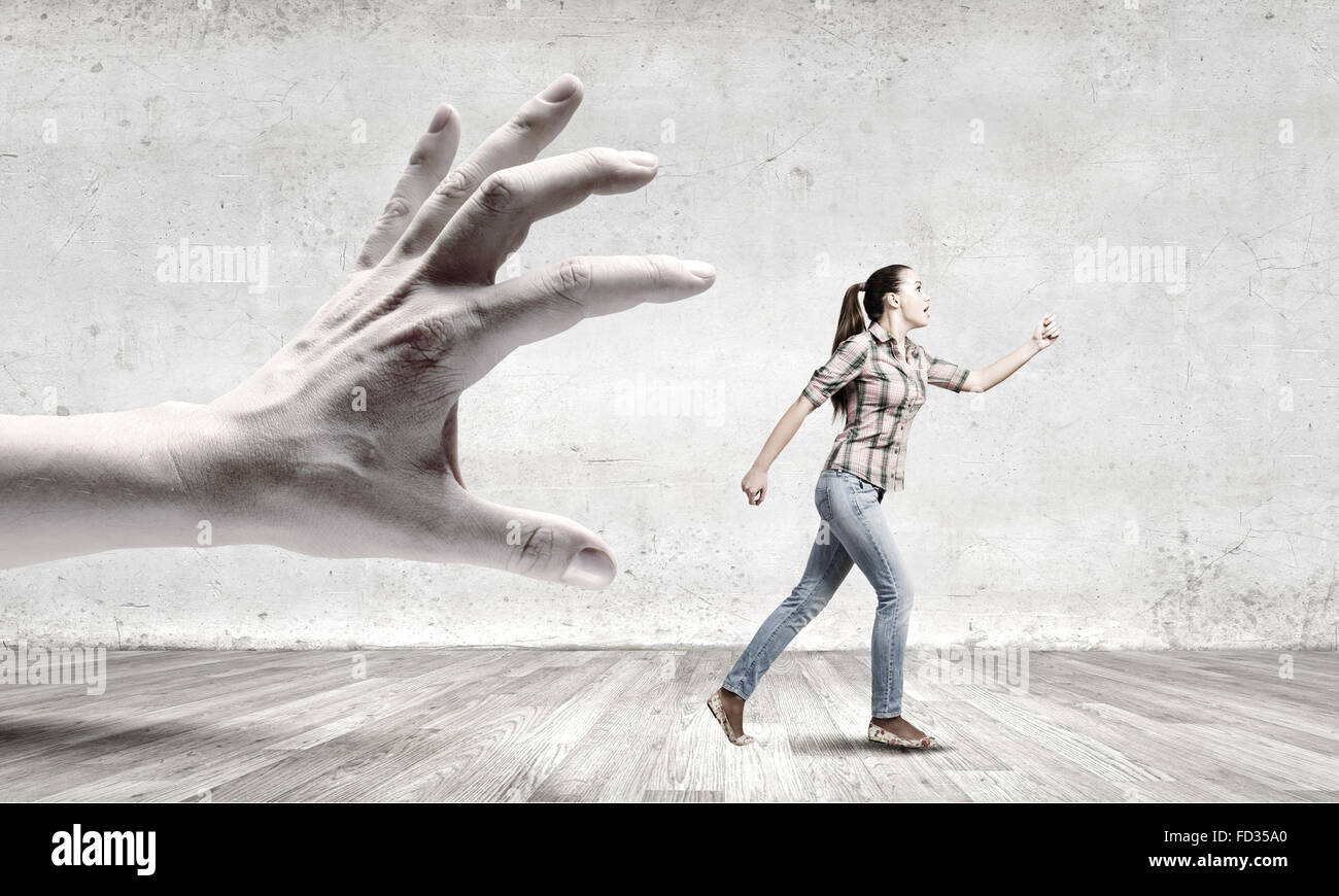 Young woman in casual courir loin de grosse main Banque D'Images