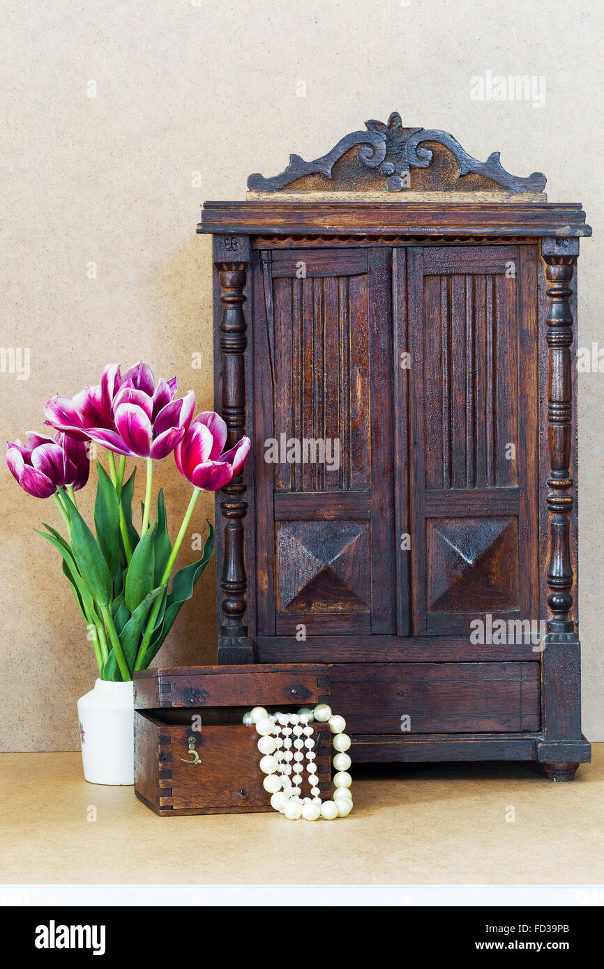 Tulipes fleurs violet vif vase blanc, vintage Ancienne armoire et coffre en bois avec des perles Banque D'Images
