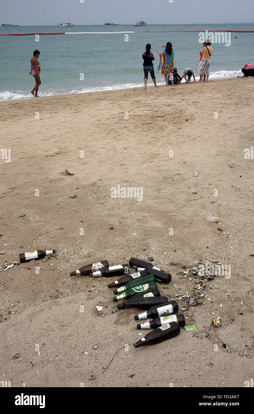 Les bouteilles de bière vides abandonnées jonchent la plage à Pattaya en Thaïlande avec les touristes en photo pagayer dans le mer. Banque D'Images