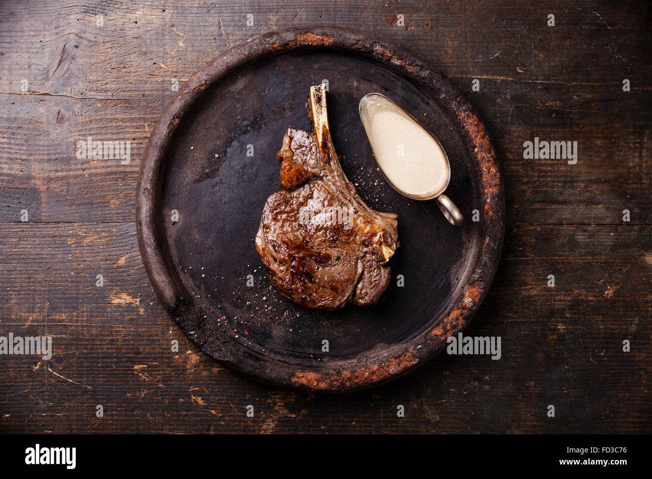Ribeye Steak sur l'os avec sauce au piment sur plaque de pierre sur fond de bois Banque D'Images