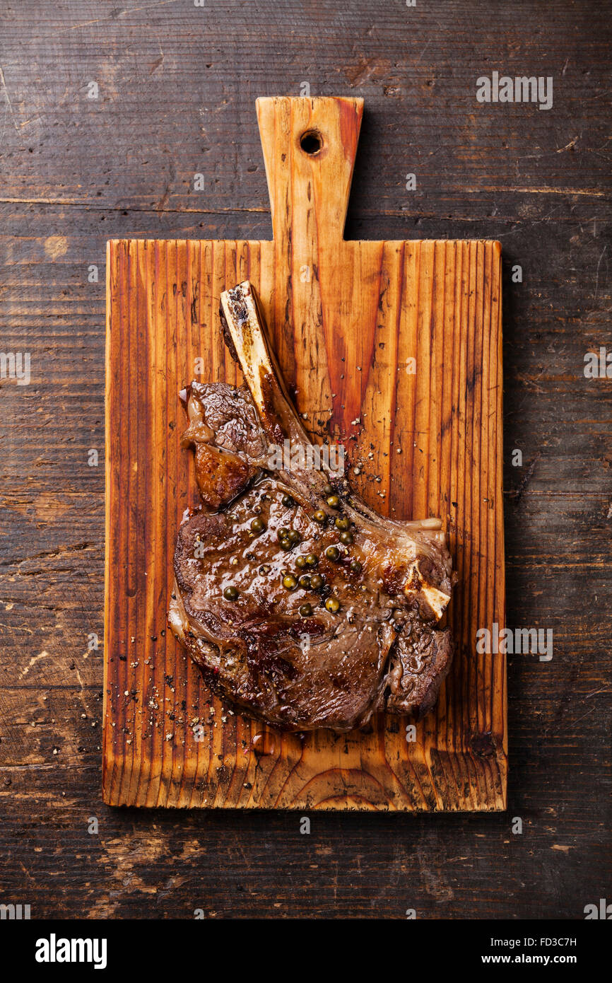 Ribeye Steak sur l'os avec sa sauce au poivre noir sur fond de bois Banque D'Images