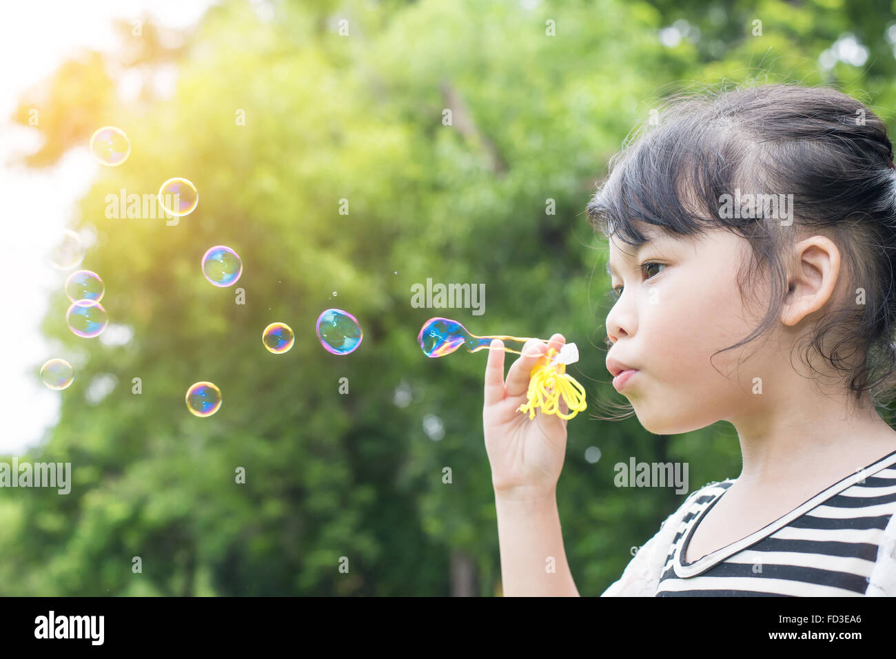 Petite fille asiatique soufflant des bulles de savon dans Green Park Banque D'Images