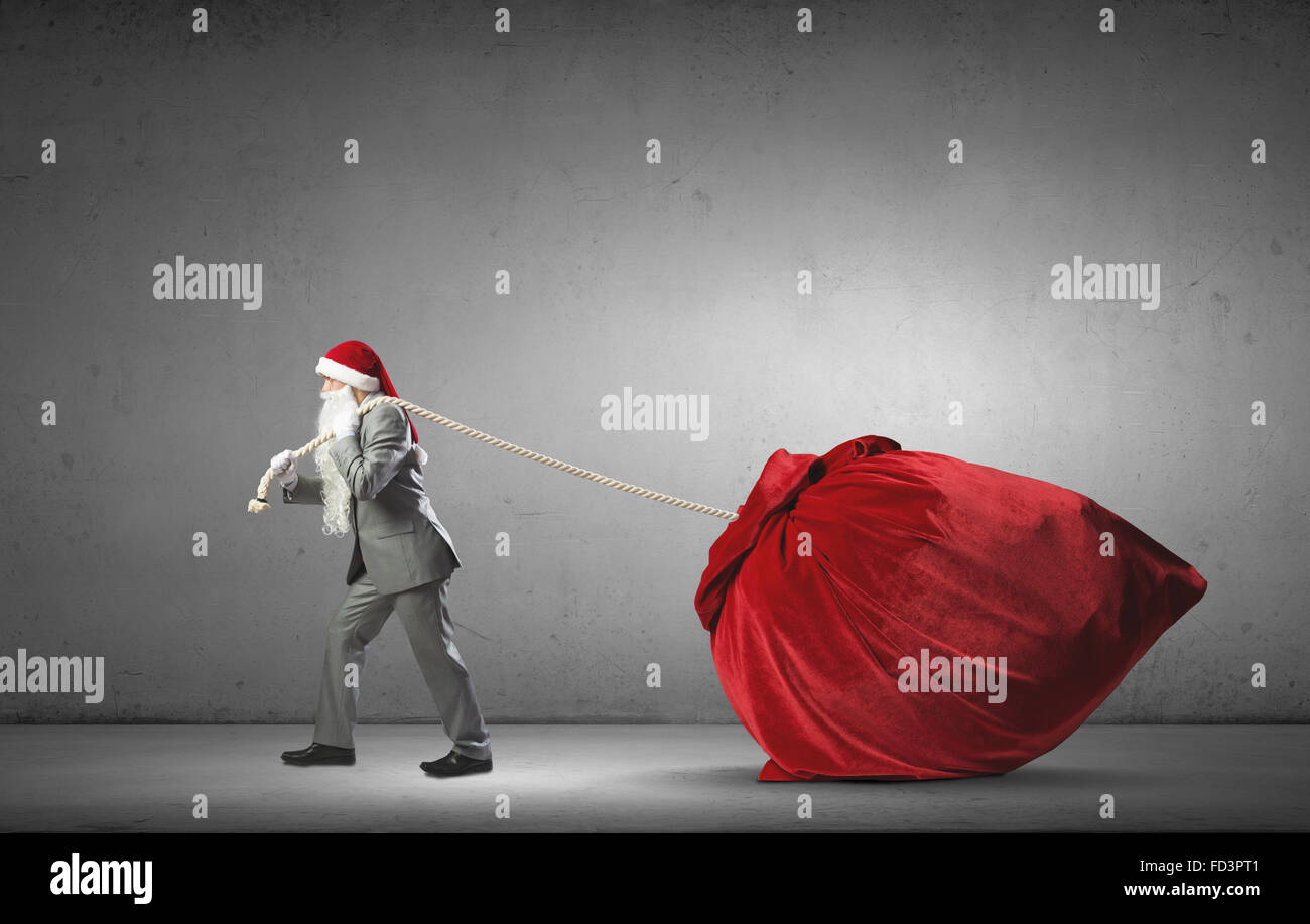 Businessman in Santa hat tirant grand sac rouge Banque D'Images Businessman in Santa hat tirant grand sac rouge Banque D'Images