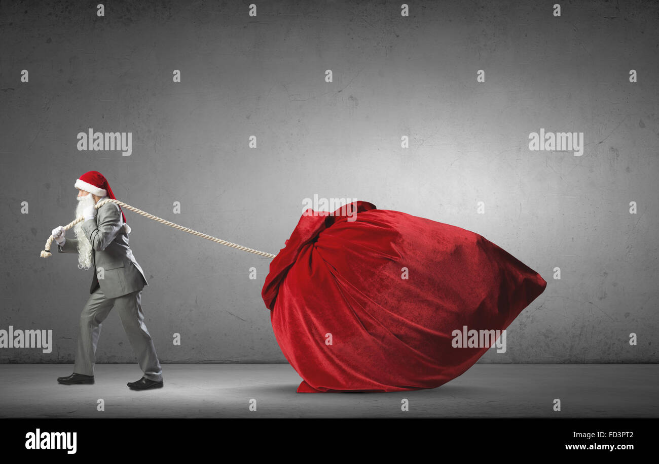 Businessman in Santa hat tirant grand sac rouge Banque D'Images Businessman in Santa hat tirant grand sac rouge Banque D'Images