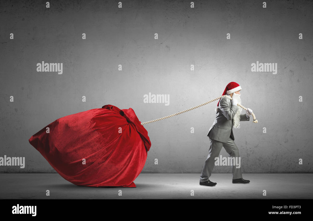 Businessman in Santa hat tirant grand sac rouge Banque D'Images Businessman in Santa hat tirant grand sac rouge Banque D'Images