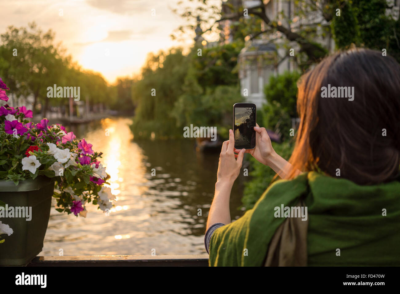 Le tourisme des jeunes femmes à Amsterdam Prendre des photos à un magnifique coucher de soleil sur un pont'jeunes femmes à Amsterdam prendre pict Banque D'Images