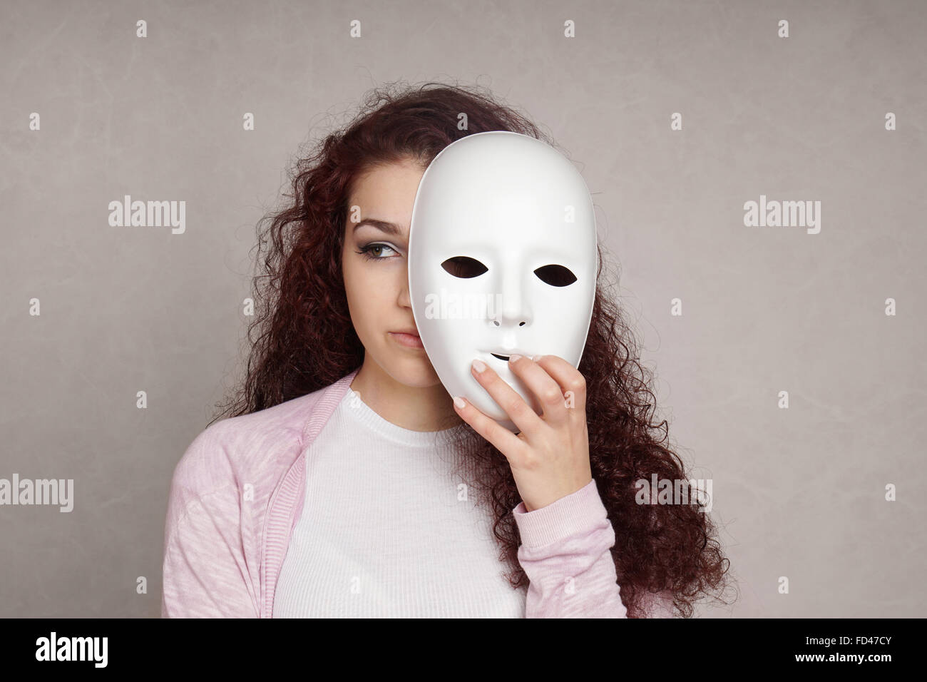 Sad girl se cacher derrière le masque Banque D'Images