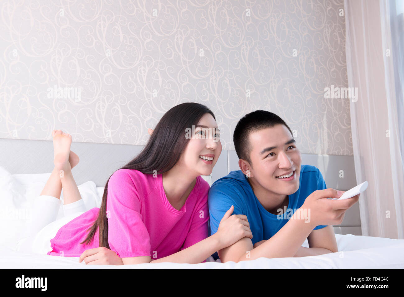 Jeune couple watching TV in bed Banque D'Images