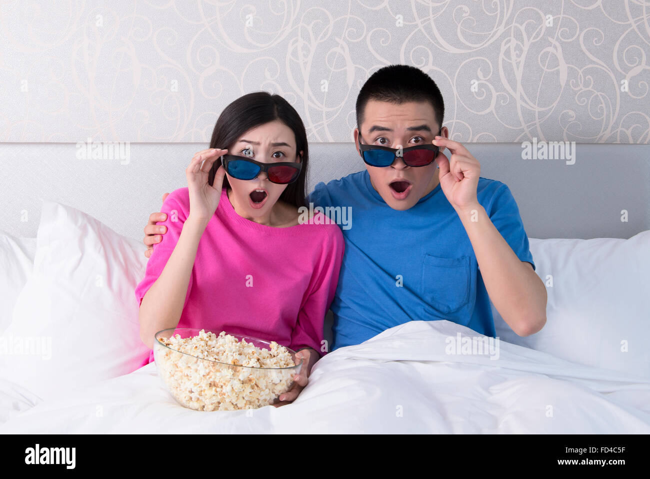 Jeune couple watching TV 3D au lit Banque D'Images