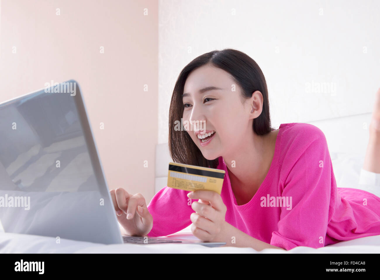 Young woman shopping online in bed Banque D'Images