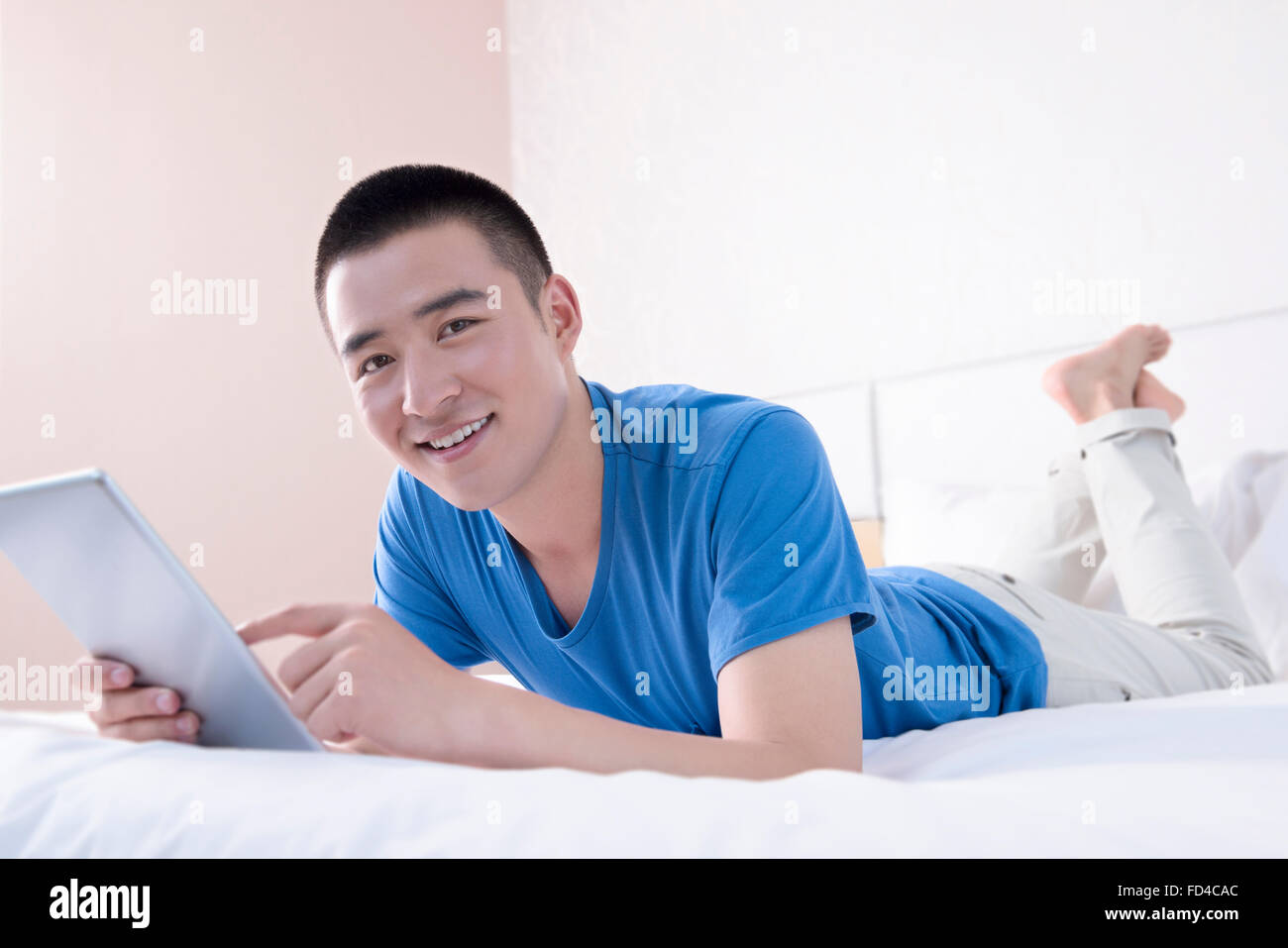 Young man using digital tablet in bed Banque D'Images