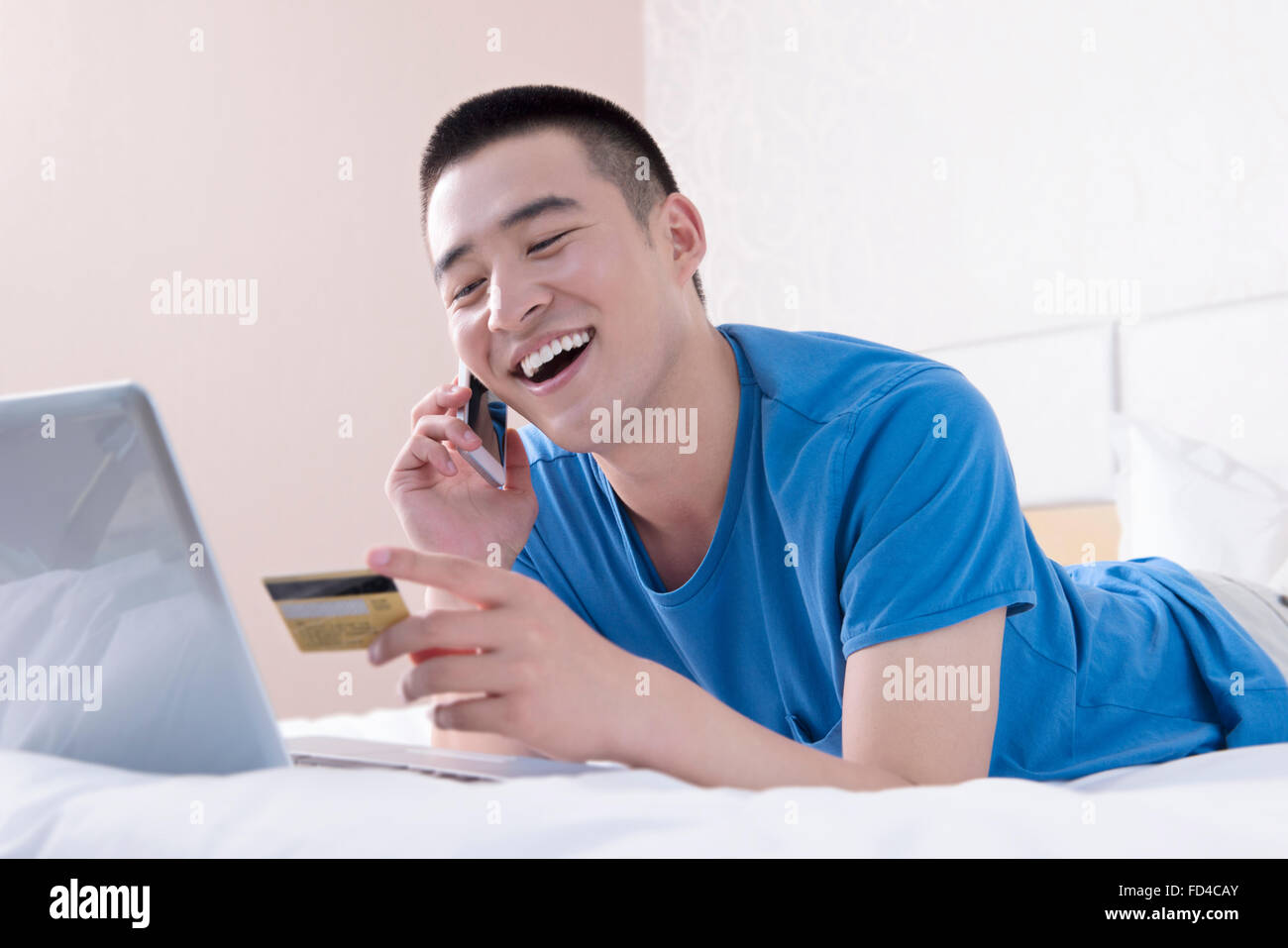 Young man using laptop et smart phone in bed Banque D'Images
