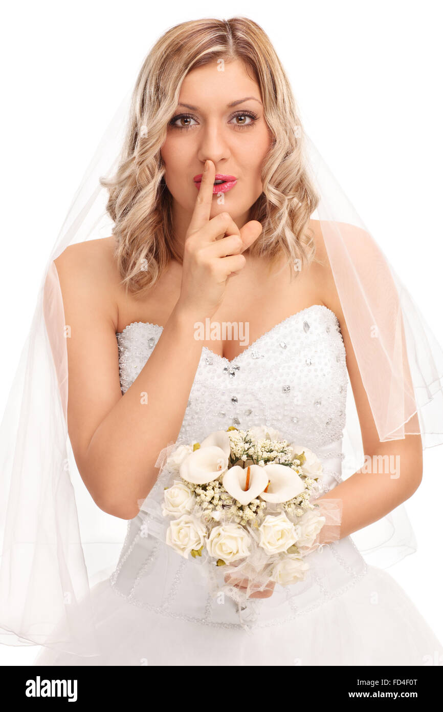 Shot verticale d'une jeune blonde bride tenant une fleur de mariage et d'un doigt sur ses lèvres isolé sur fond blanc Banque D'Images
