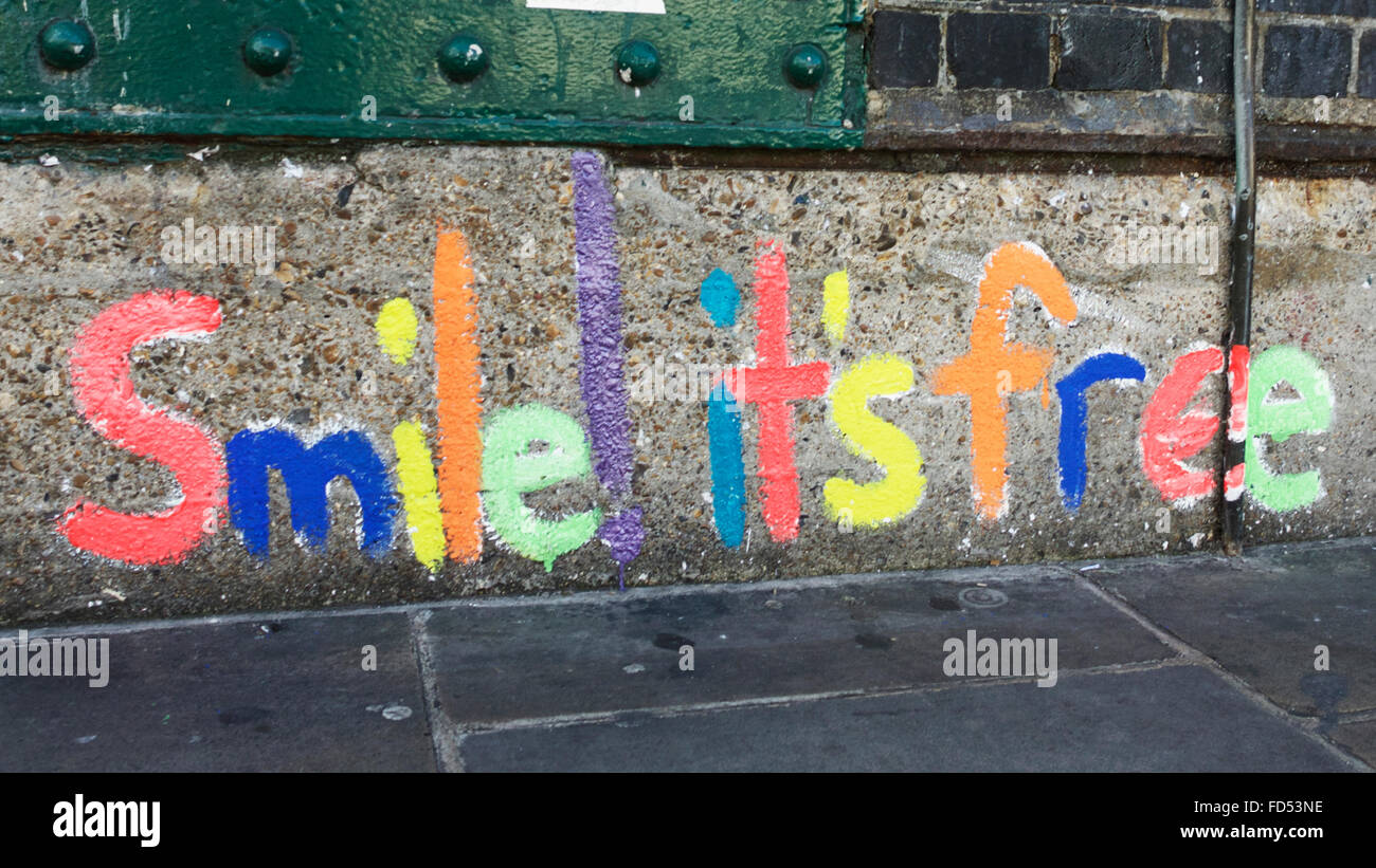 « Smile its Free » peint sur un mur dans Brick Lane, concept de bonheur. Couleurs et formes. La positivité du bonheur. Pleine conscience. Graffiti Londres. Banque D'Images