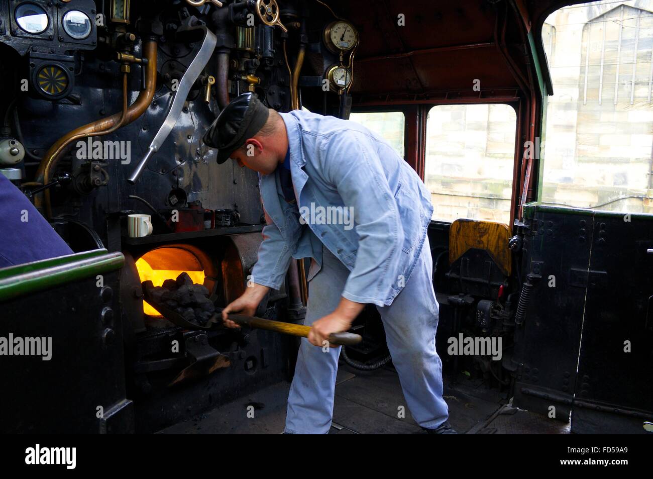 Stoker alimenter le feu fort de LMS train à vapeur classe couronnement Princesse 46233 la duchesse de Sutherland. Banque D'Images