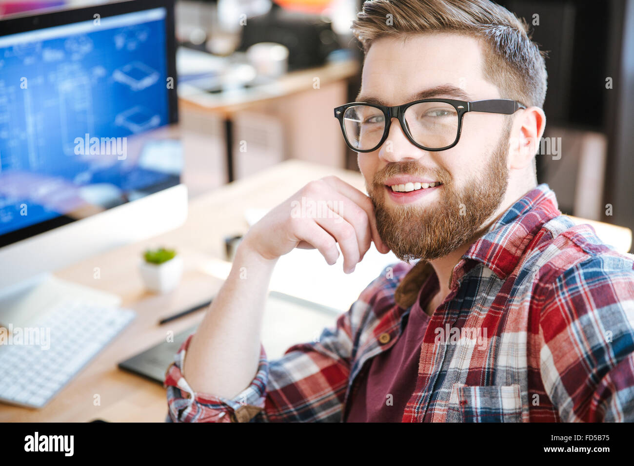 Happy young man with beard dans les verres et de la conception de projet sur son ordinateur Banque D'Images