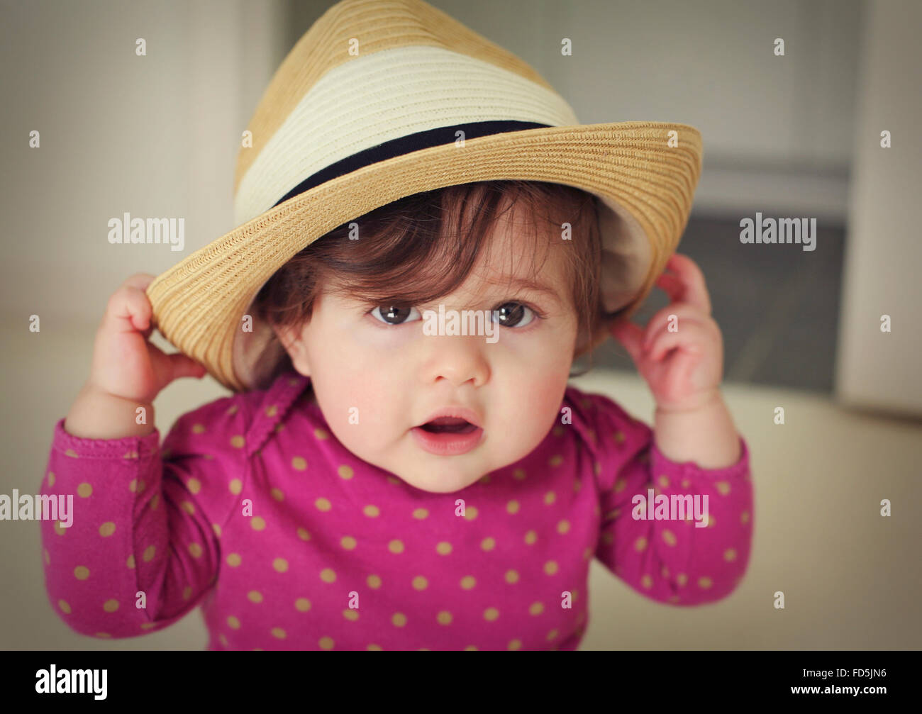 Adorable baby girl holding un chapeau de paille sur sa tête. Banque D'Images