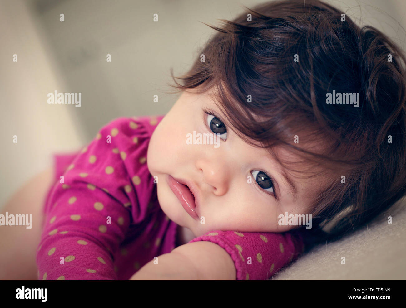 Bébé fille précieux portant sur son bras regardant la caméra avec un visage triste. Banque D'Images