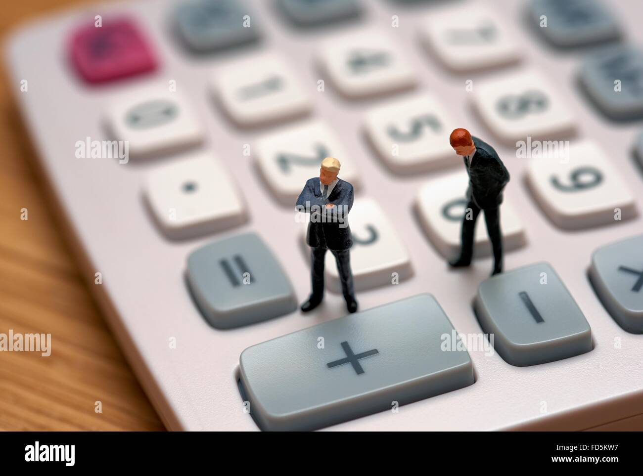 Figurine miniature en costumes hommes debout sur une calculatrice Banque D'Images