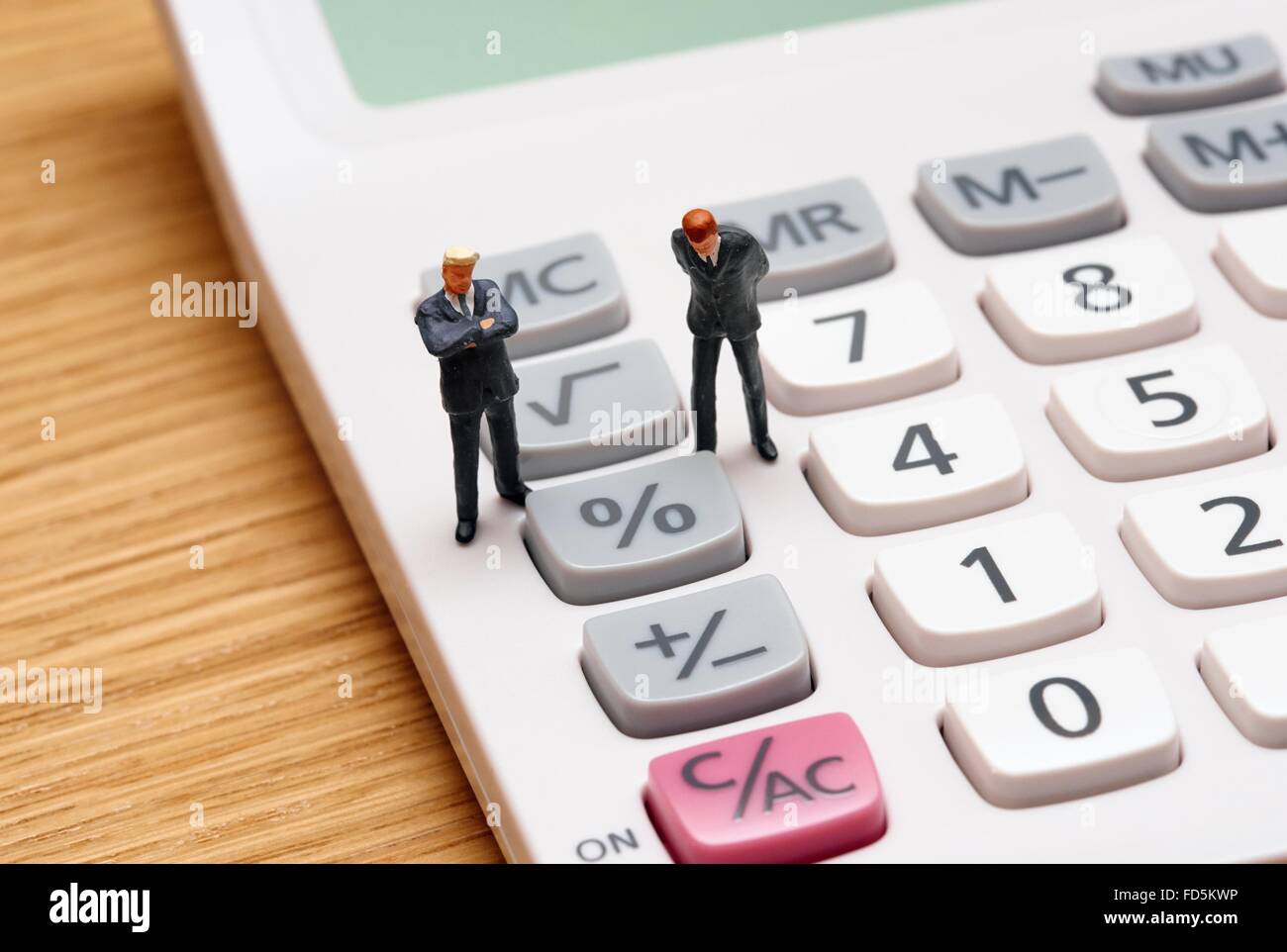 Figurine miniature en costumes hommes debout sur une calculatrice Banque D'Images