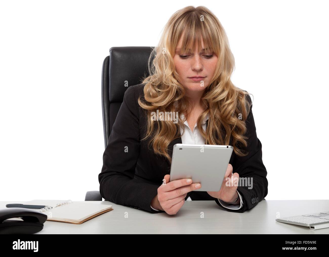 Young businesswoman working online à l'aide d'un ordinateur tablette de poche alors qu'elle surfe sur internet avec une expression grave Banque D'Images