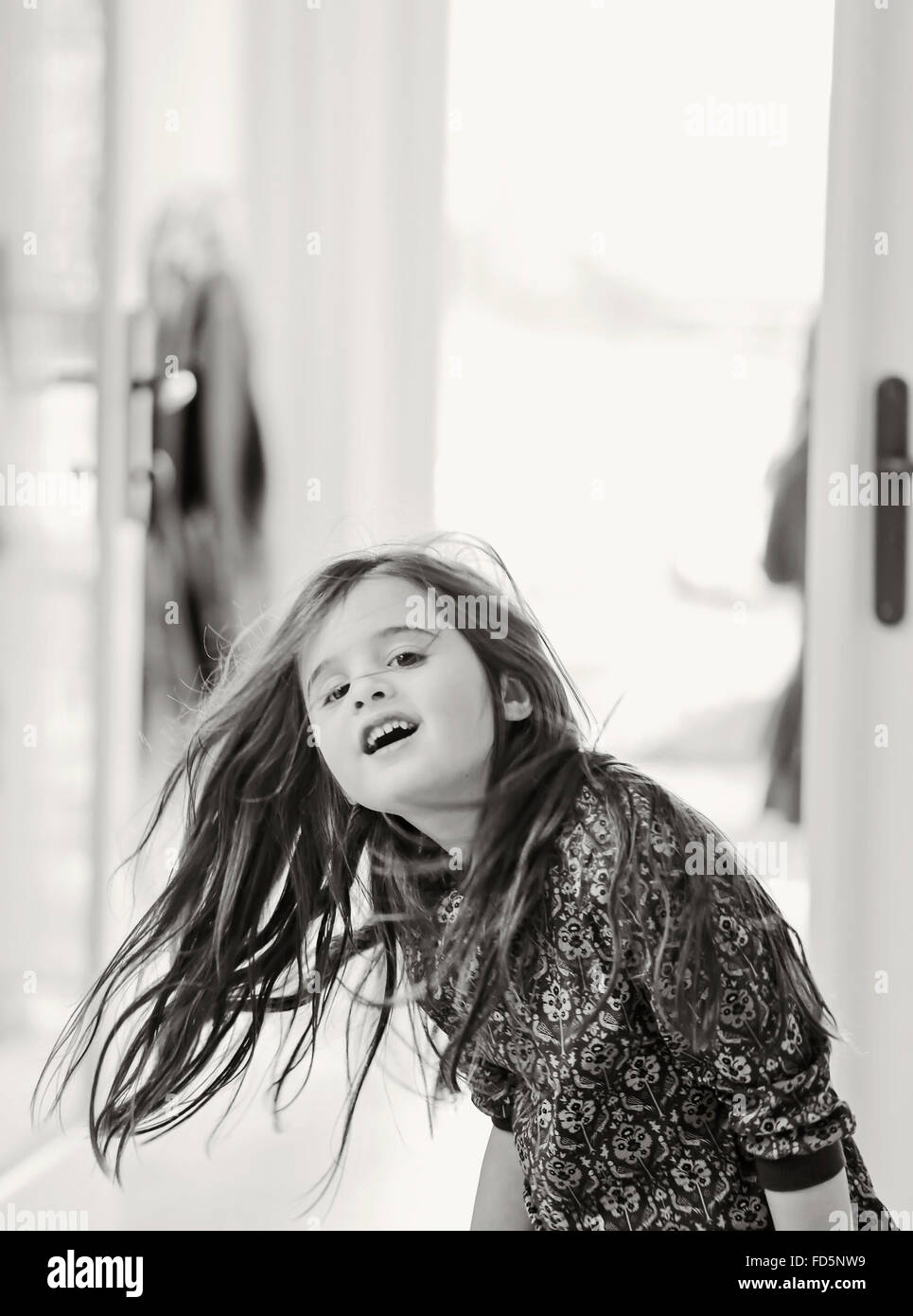 Image en noir et blanc d'une jeune fille et danser, balançant ses longs cheveux bruns et souriant. Banque D'Images