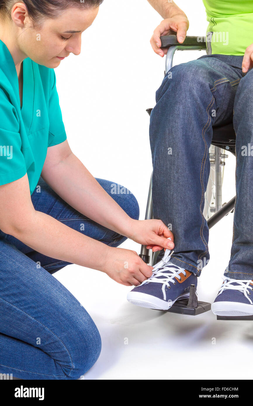 Infirmière aide un jeune handicapé en fauteuil roulant s'habiller. Banque D'Images