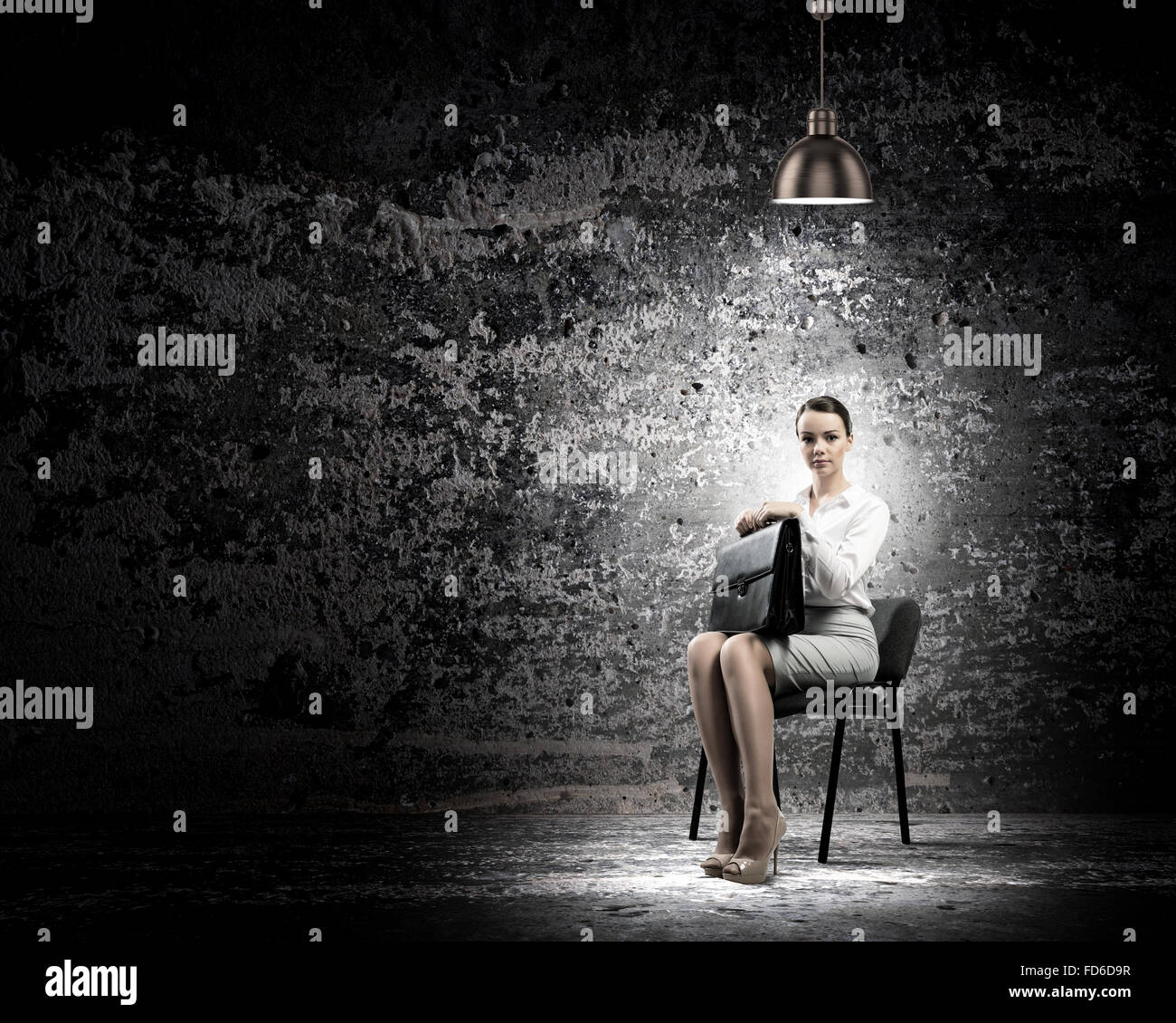 Image de young businesswoman sitting on chair sous tache de lumière Banque D'Images