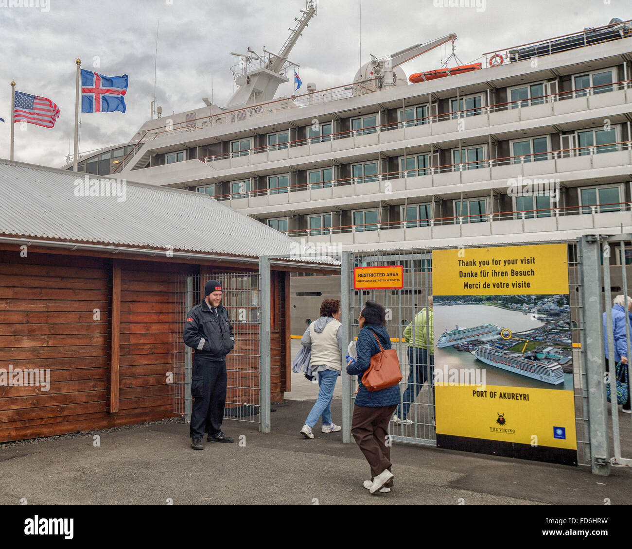 Akureyri, Islande du Nord, l'Islande. 1er août 2015. Les passagers de la Compagnie du Ponant navire de croisière de luxe Le Boreal passer au travers d'une clôture de protection surveillée par un garde de sécurité dans le nord-est de port d'Akureyri, Islande, le deuxième plus grande zone urbaine dans le fjord Eyjafjordur. C'est un important centre de pêche où le tourisme est devenu un secteur croissant de l'économie. © Arnold Drapkin/ZUMA/Alamy Fil Live News Banque D'Images