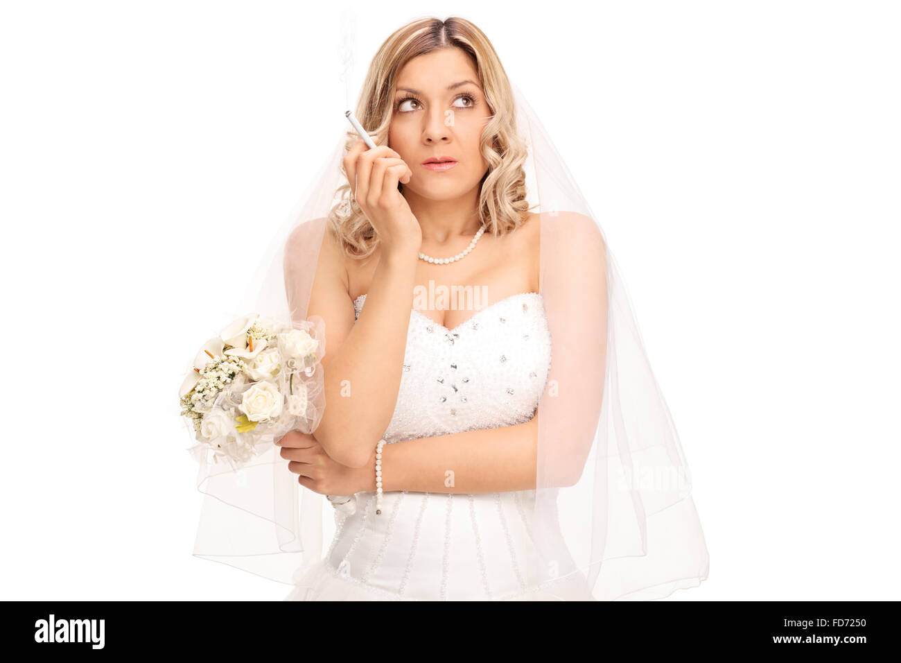 Jeune mariée nerveux dans une robe de mariée blanche tenant un bouquet et fumer une cigarette isolé sur fond blanc Banque D'Images