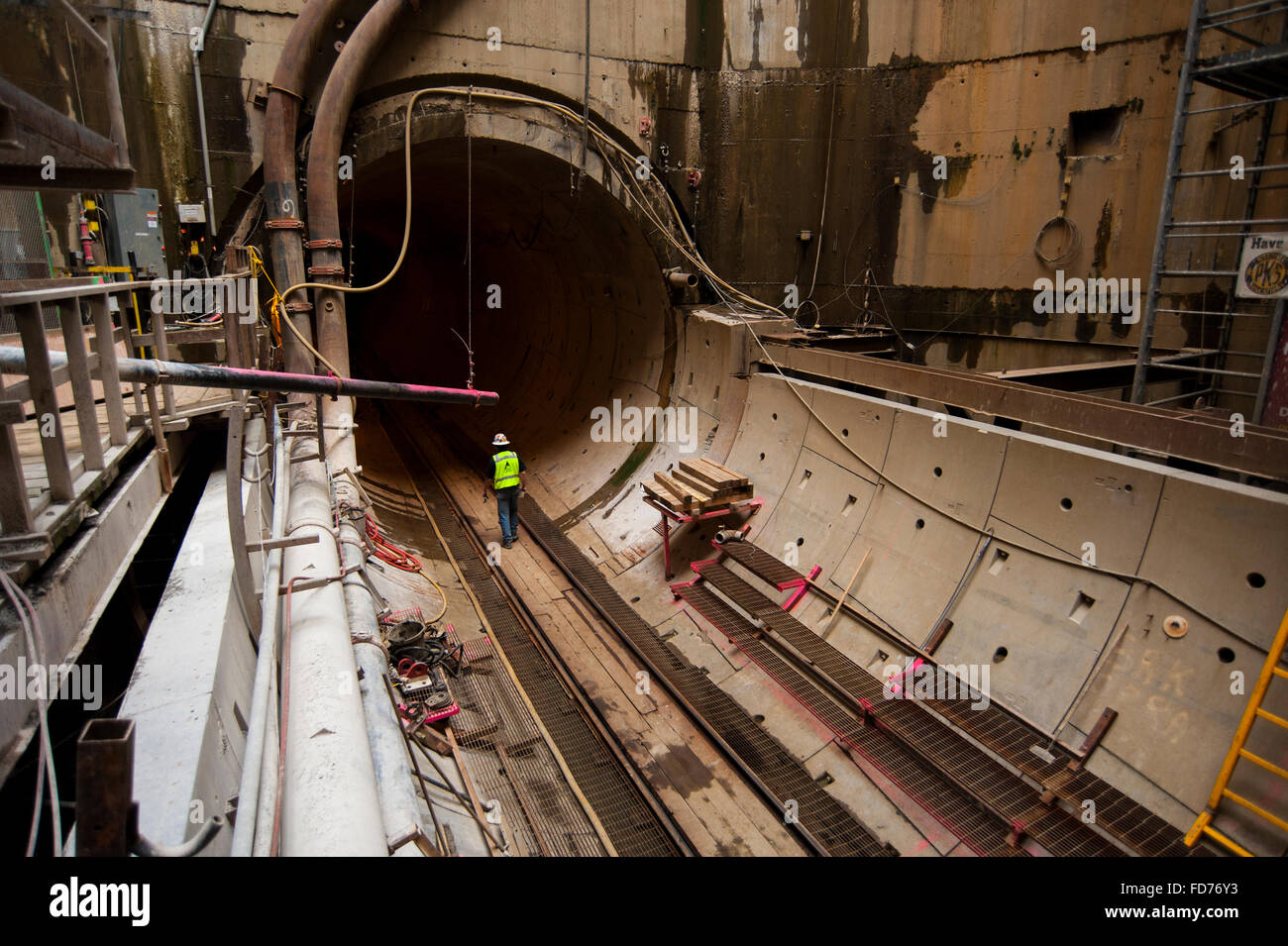 Un travailleur de l'échelle d'une montre le gros tuyau déversoir d'tunnel project Banque D'Images
