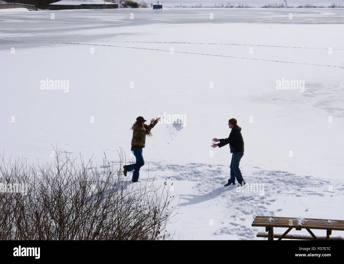 Les jeunes jouant sur un lac gelé de jeter un grand bal de neige. Banque D'Images