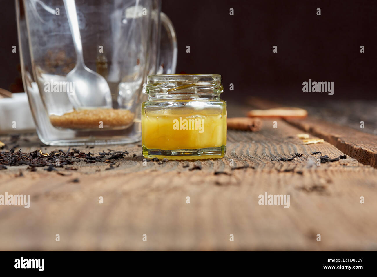 Miel de tournesol jaune en face de plateau verre avec une cuillère et le sucre brun sur la vieille table en bois Banque D'Images