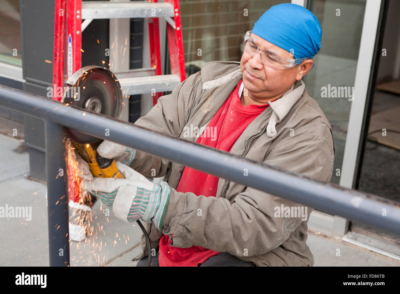 Construction Worker cutting steel pipe avec outil Meuleuse angulaire - USA Banque D'Images