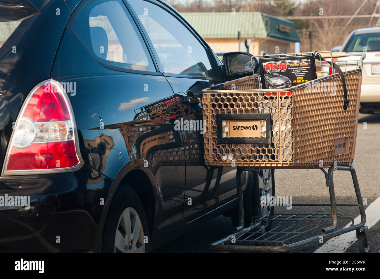 Chariot d'épicerie s'appuyant sur voiture en stationnement - USA Banque D'Images
