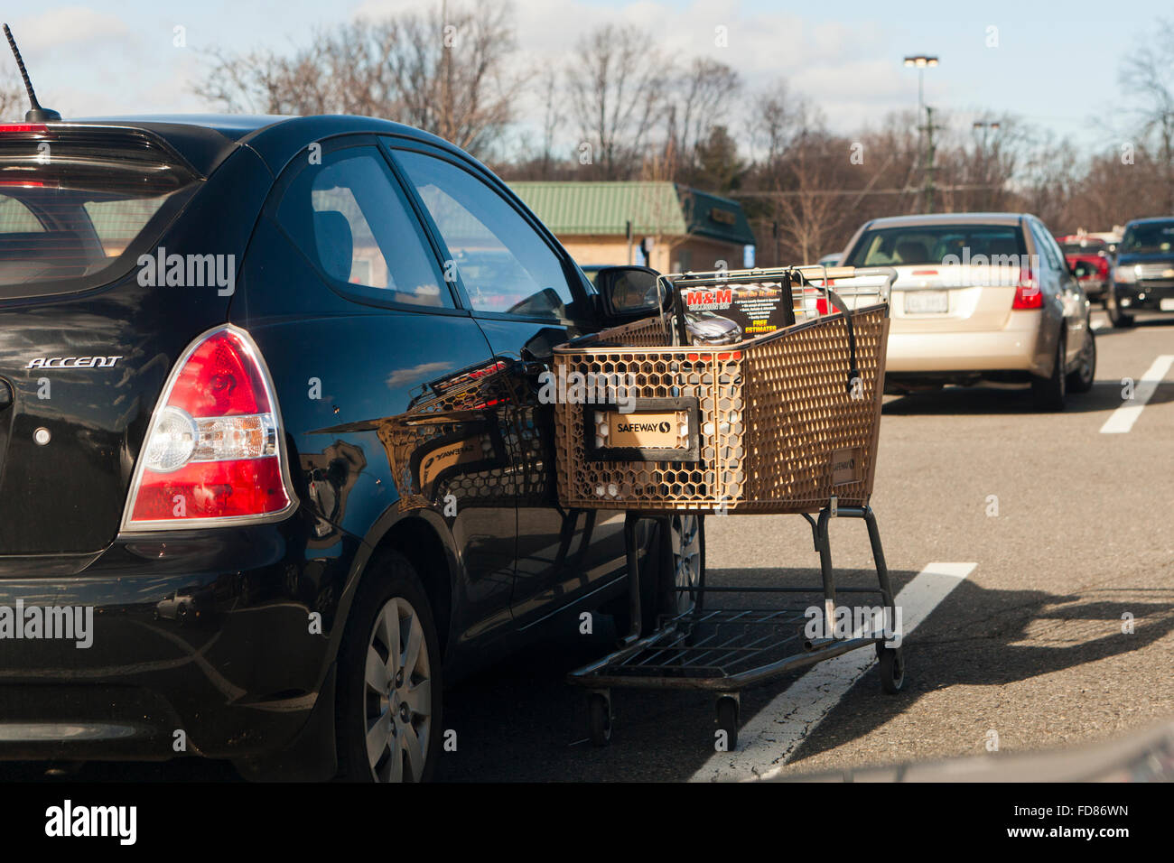 Chariot d'épicerie s'appuyant sur voiture en stationnement - USA Banque D'Images