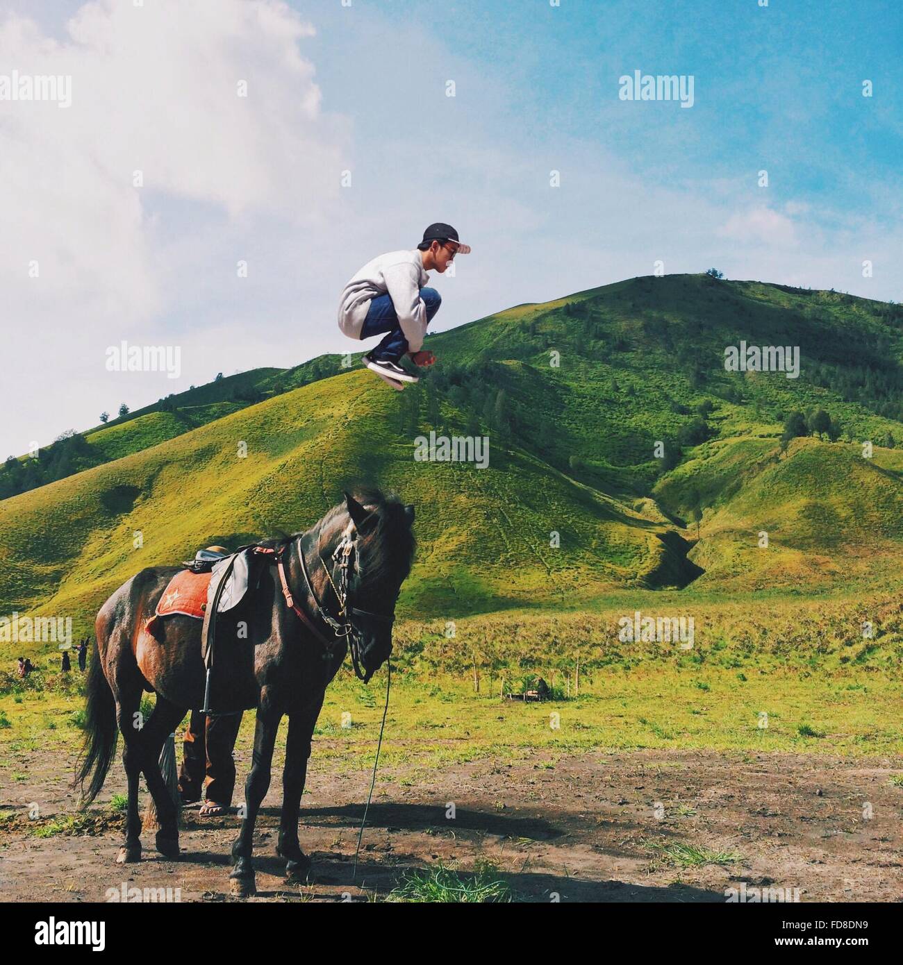 Vue de côté de l'homme qui saute dans les airs contre Green Mountains Banque D'Images