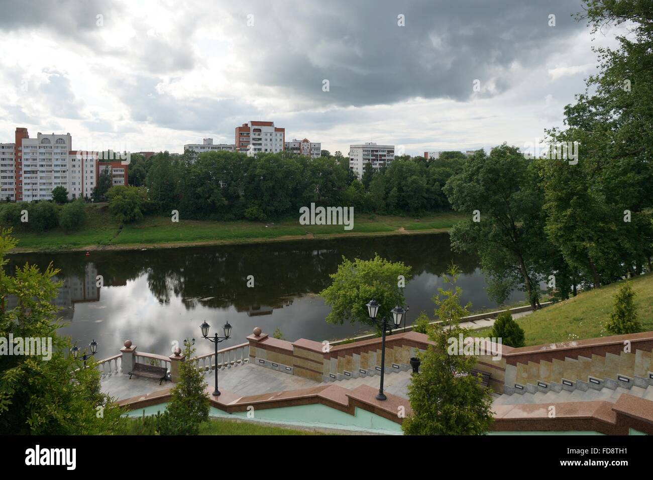 Dvina occidentale riverfront avec arbres et maisons apertment reflétant dans l'eau et ciel couvert, Vitebsk, en Biélorussie. Banque D'Images