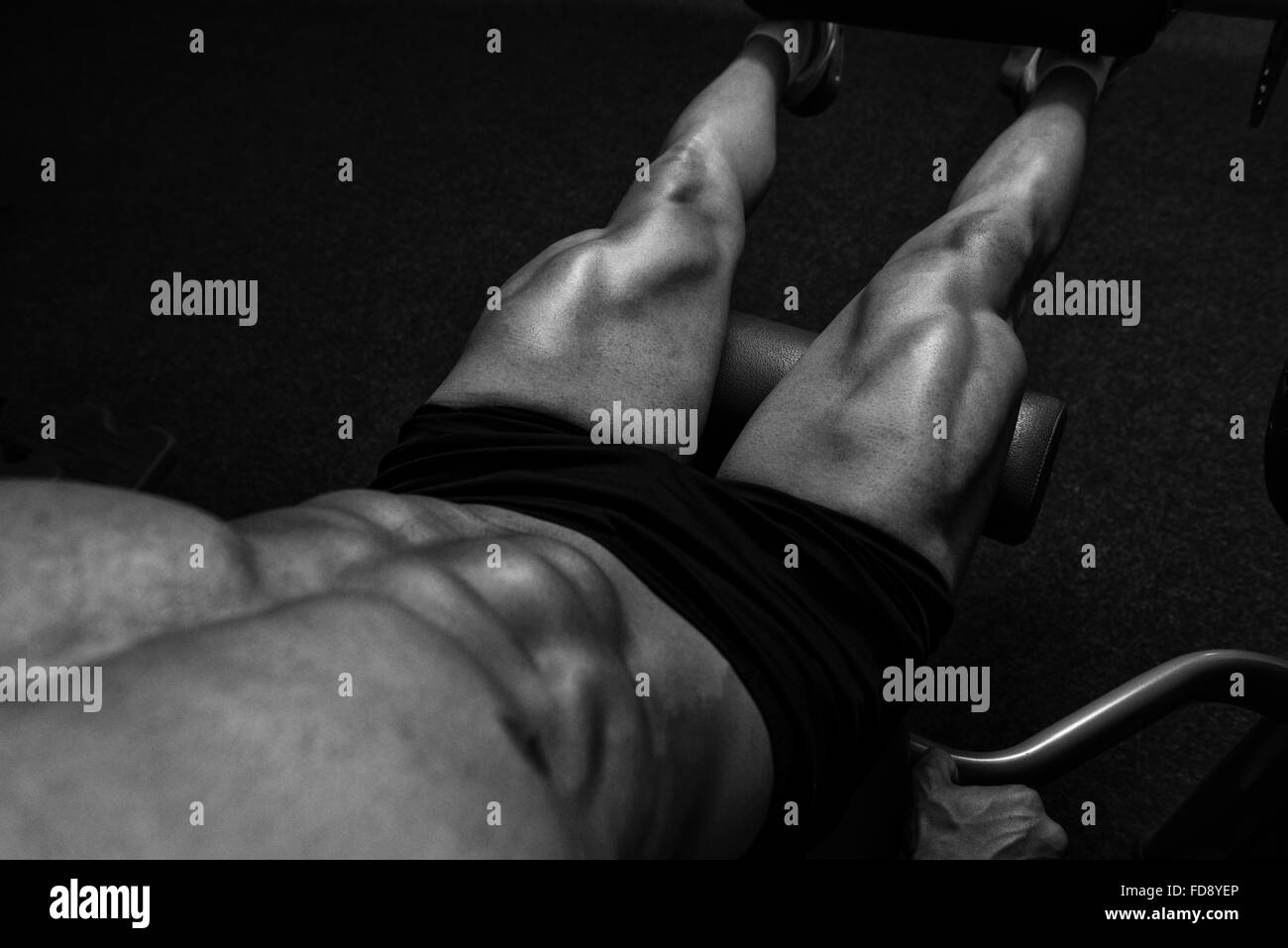 Jeune homme attrayant faisant les jambes avec la machine In Gym Banque D'Images