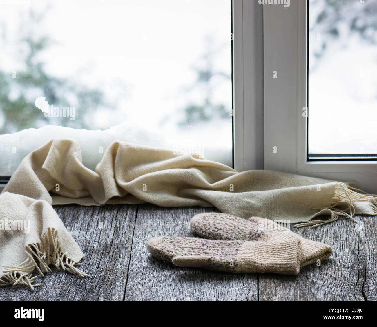 Écharpe et mitaines en laine beige situé sur un rebord de fenêtre en bois stylisés. Winter concept de confort et de détente. Banque D'Images