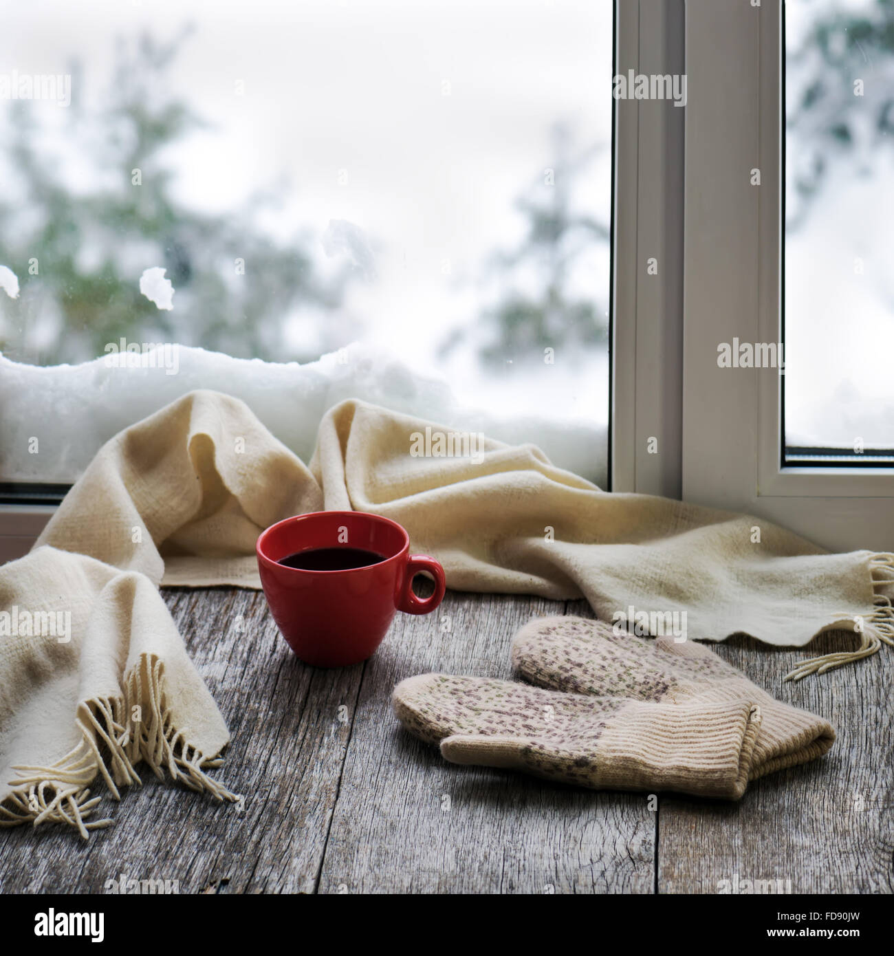 La tasse de café ou de thé, beige écharpe et mitaines de womans sont situés sur le rebord en bois stylisés. Un concept de confort d'hiver Banque D'Images