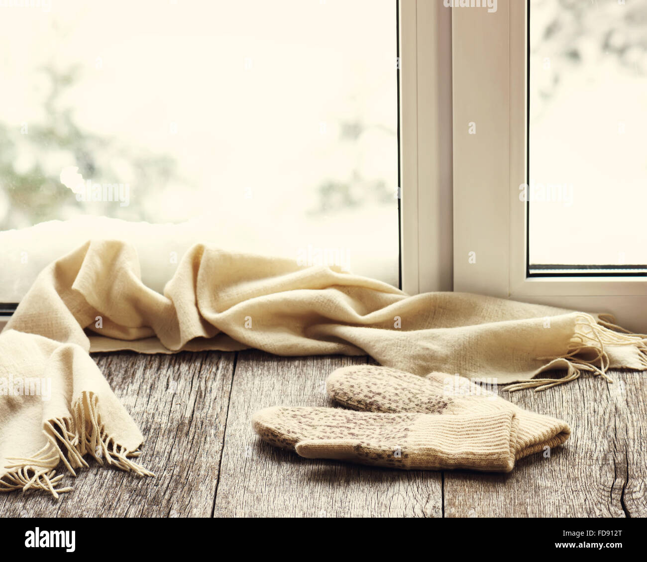 Écharpe et mitaines en laine beige situé sur un rebord de fenêtre en bois stylisés. Winter concept de confort et de détente. Photo avec retr Banque D'Images