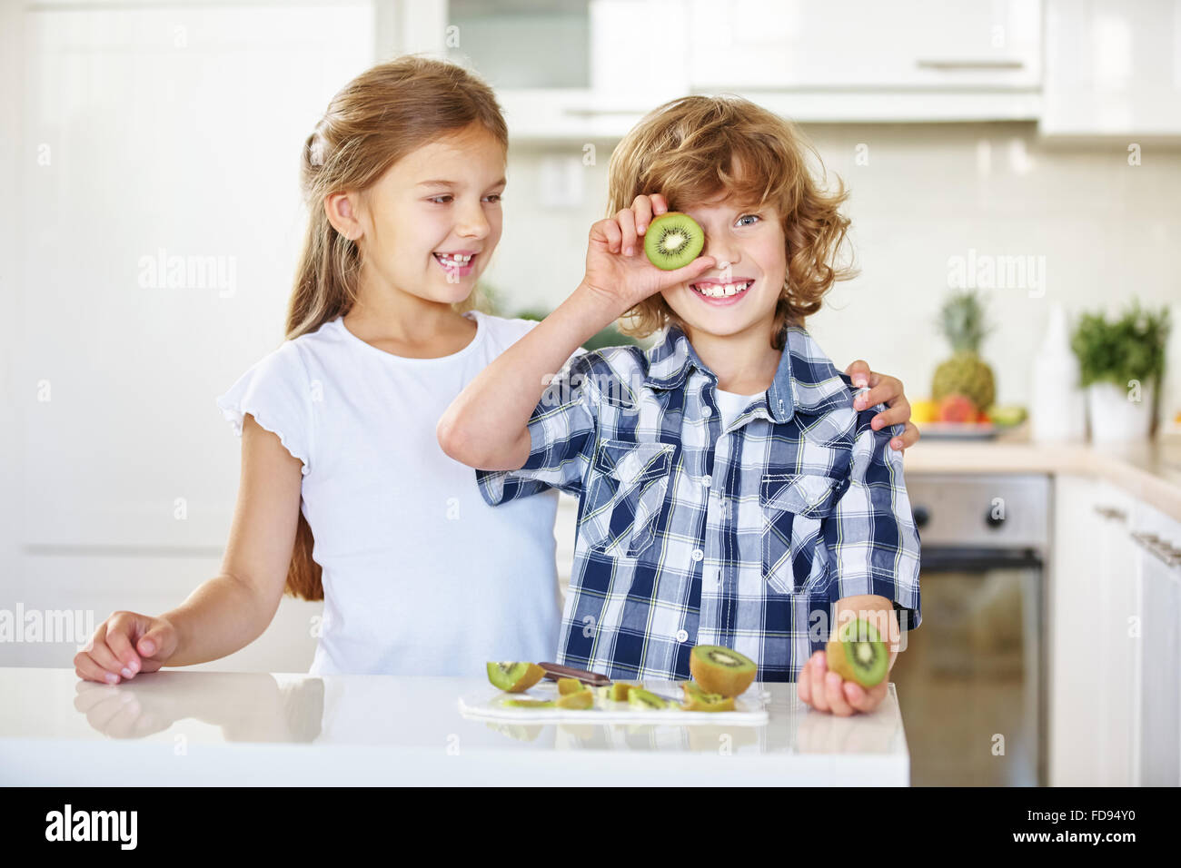 Deux enfants s'amusant avec des fruits dans la cuisine Banque D'Images